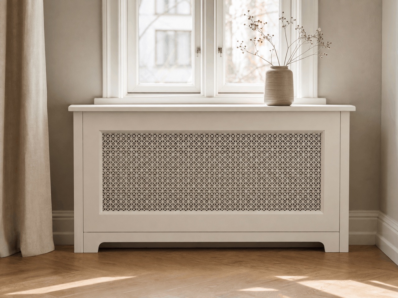 Hvid radiatorskjuler med dekorativ mønsterfront under et vindue